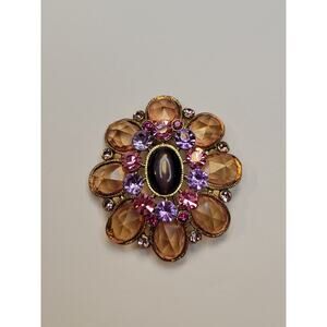 vintage-style costume jewelry brooch featuring a central oval cabochon stone